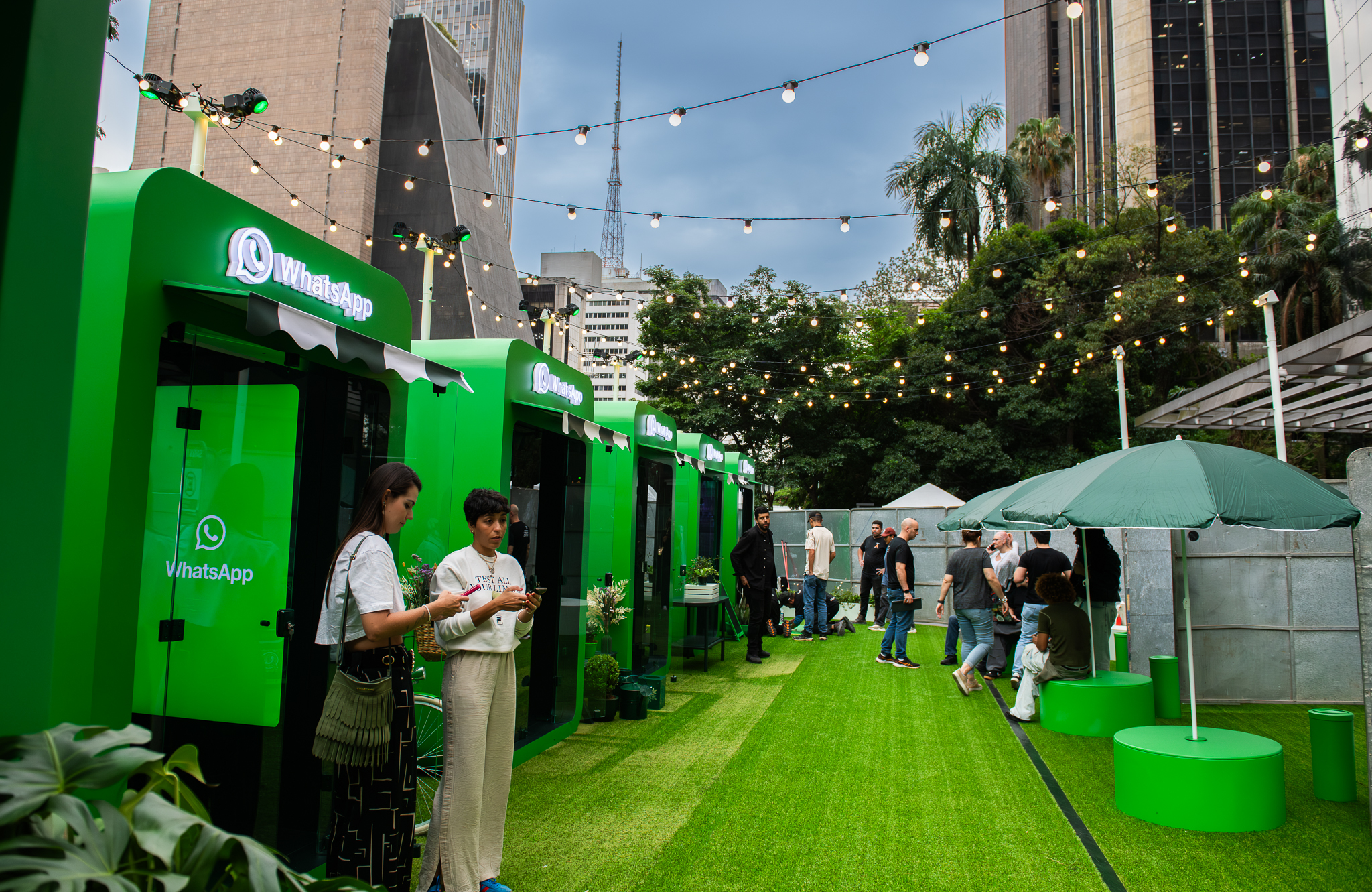 Ativação de marca WhatsApp na Avenida Paulista com quiosques verdes, gramado artificial e iluminação festiva