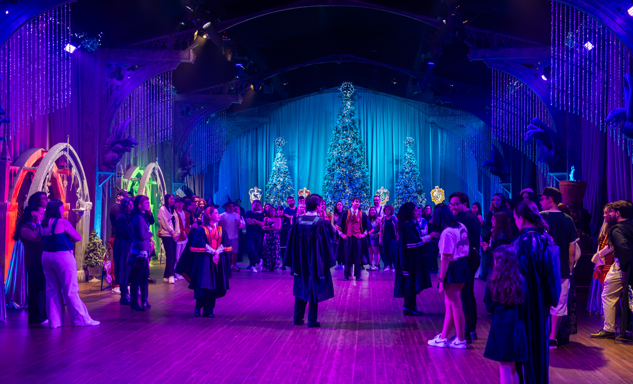 Evento temático de Harry Potter em salão decorado com árvores de Natal iluminadas e brasões das casas de Hogwarts em São Paulo.