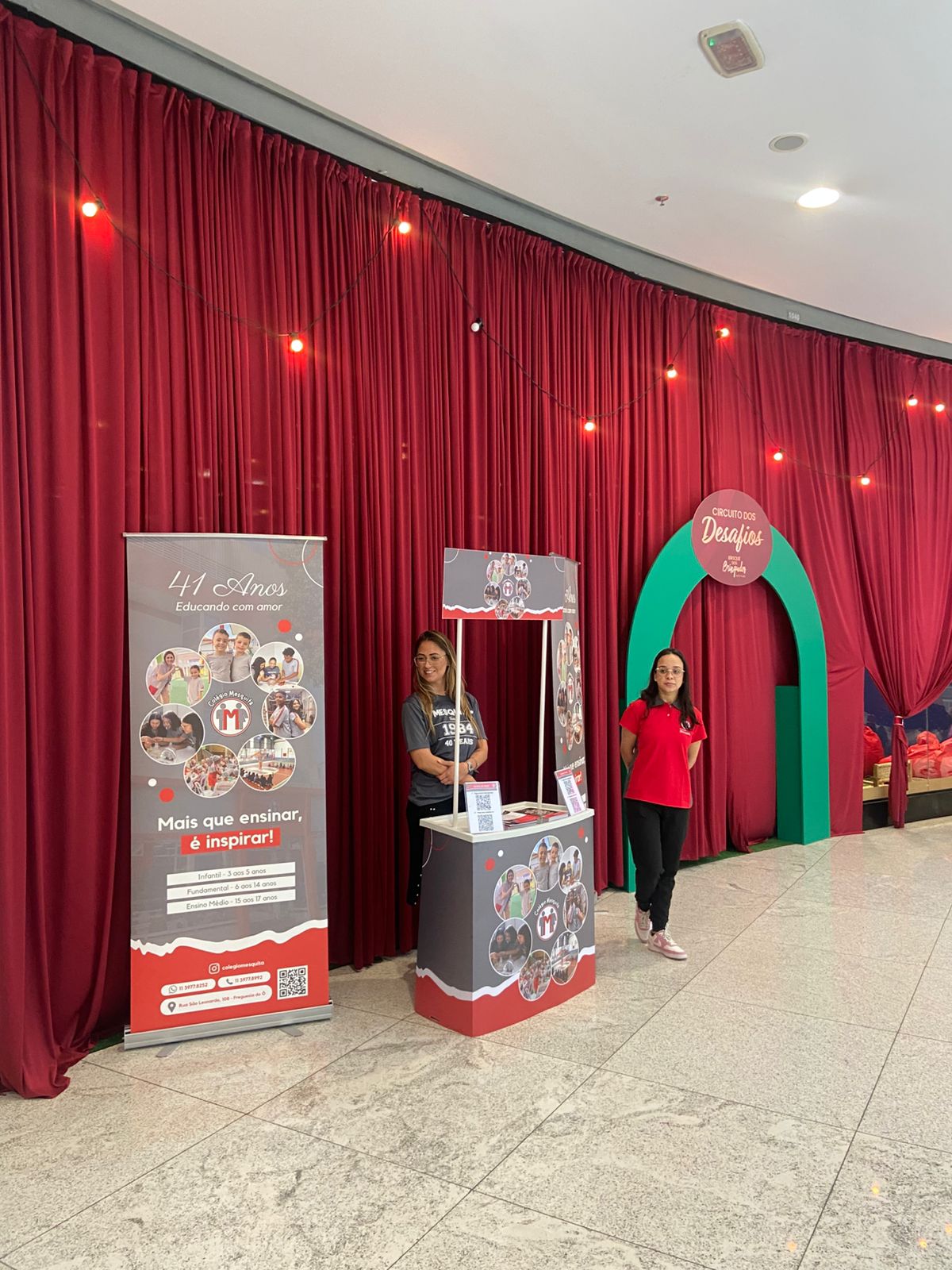 Stand de patrocínio do Colégio Mesquita em evento Circuito dos Desafios em shopping center com banner e equipe de atendimento