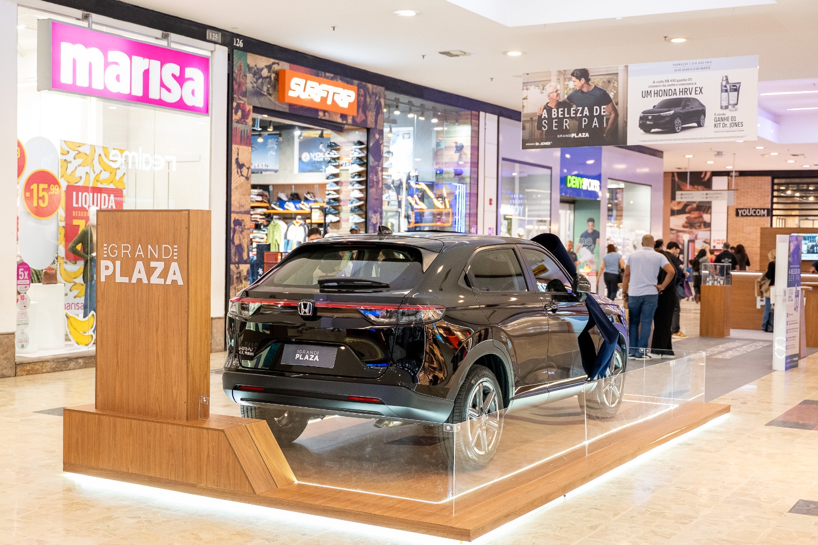 Honda HRV EX preto exposto em plataforma de madeira no corredor do Shopping Grand Plaza com campanha Dia dos Pais ao fundo