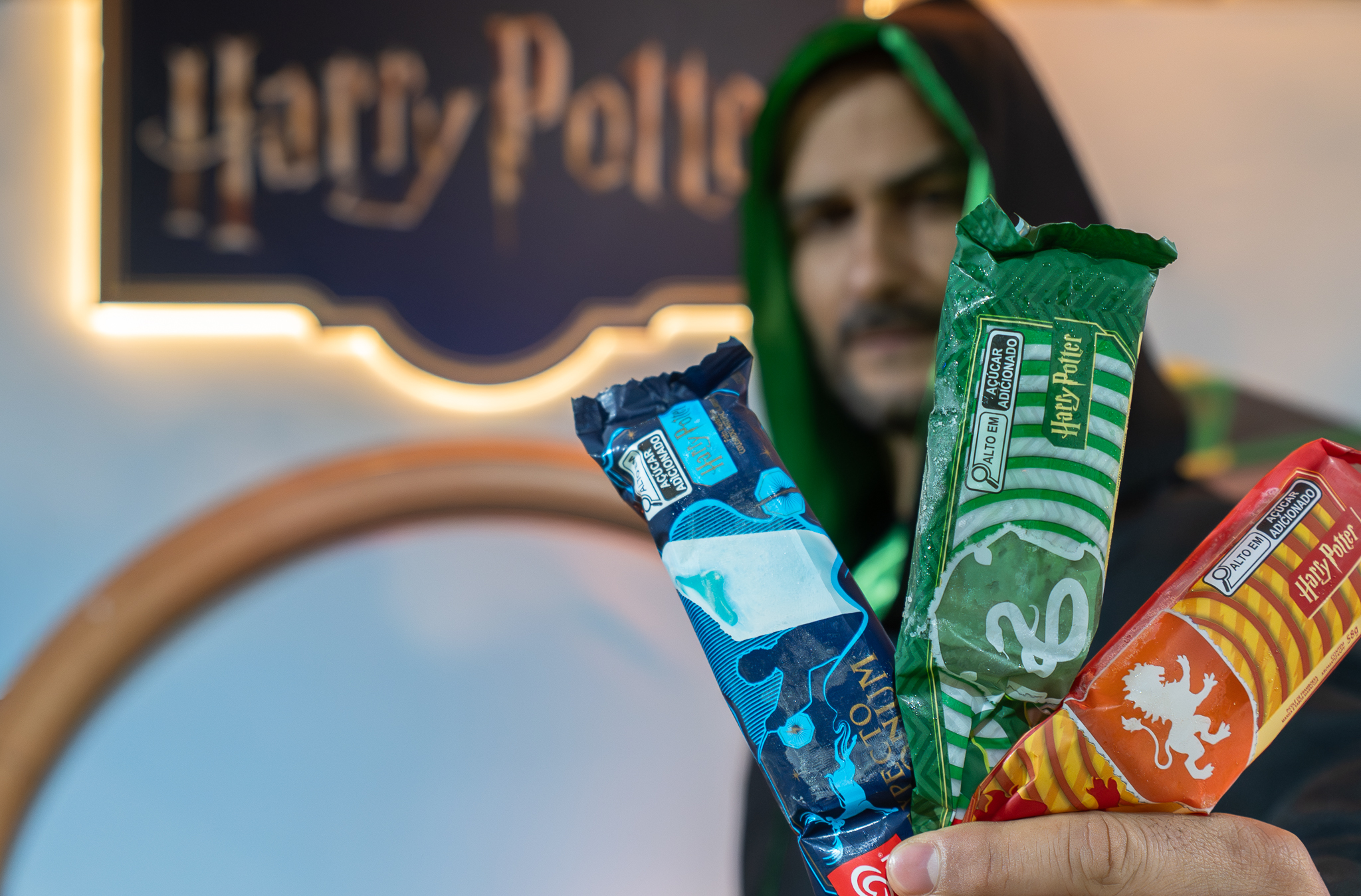 Ator caracterizado segurando produtos temáticos de Harry Potter em ativação de marca em shopping